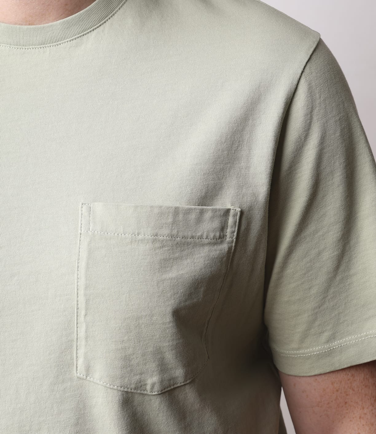 Close-up of a person wearing the Best Made Co Standard Pocket T-Shirt in Haze, showcasing its chest pocket. Only the upper torso and part of one arm are visible against a neutral background.