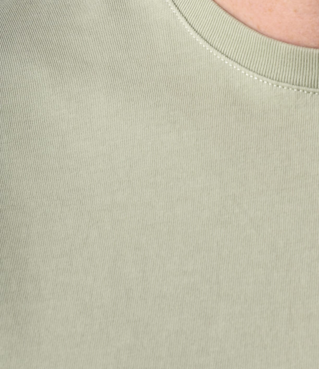 Close-up of Best Made Co's Standard Pocket T-Shirt Haze in light green, featuring a ribbed, garment-dyed texture, rounded neckline, and a glimpse of skin at the top right corner.