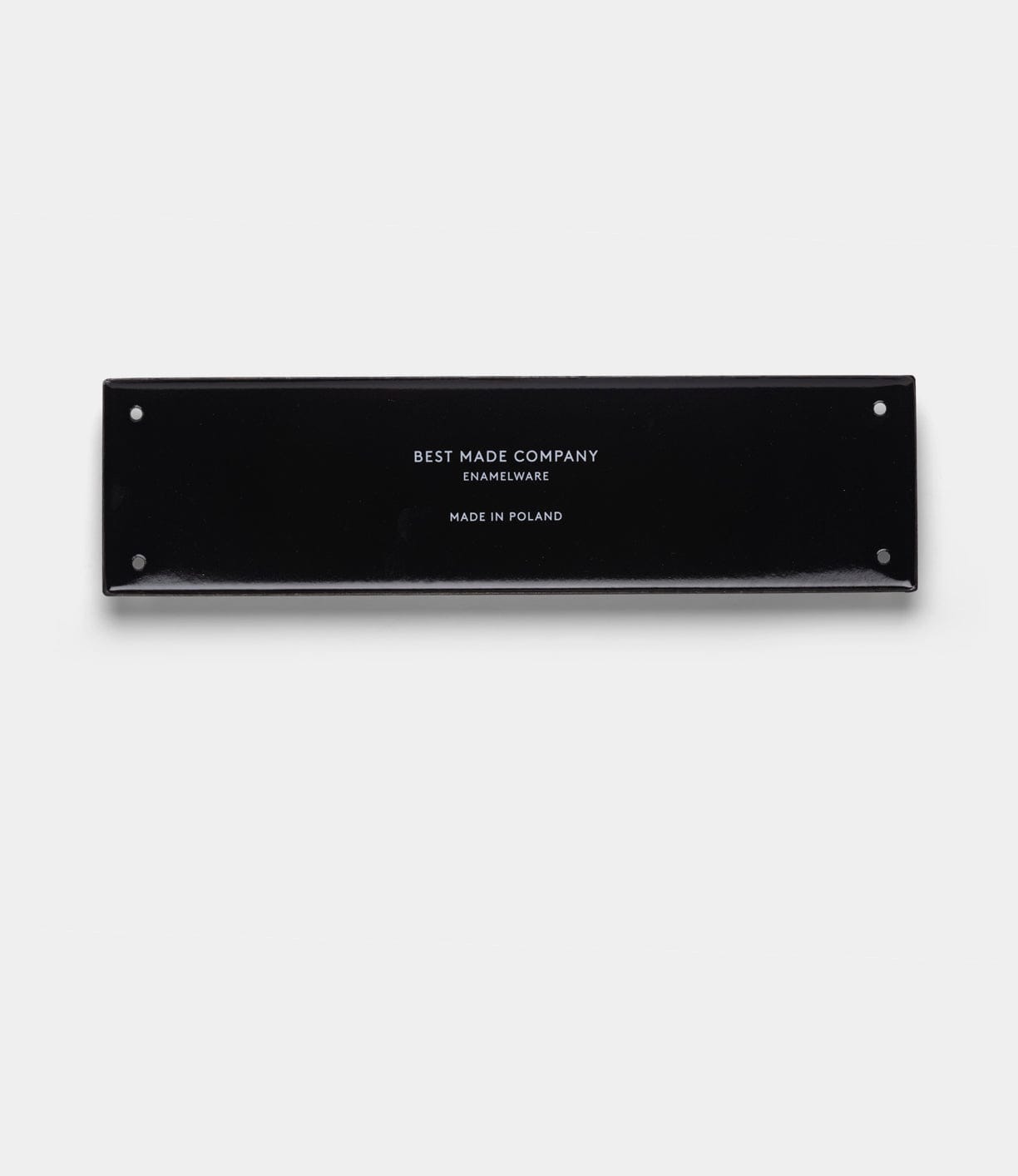 A rectangular black enamelware sign with four corner holes. The durable “Stay Sharp” Enamel Steel Sign by Best Made Co. features centered white text on a plain light gray background, reading BEST MADE COMPANY ENAMELWARE MADE IN POLAND.