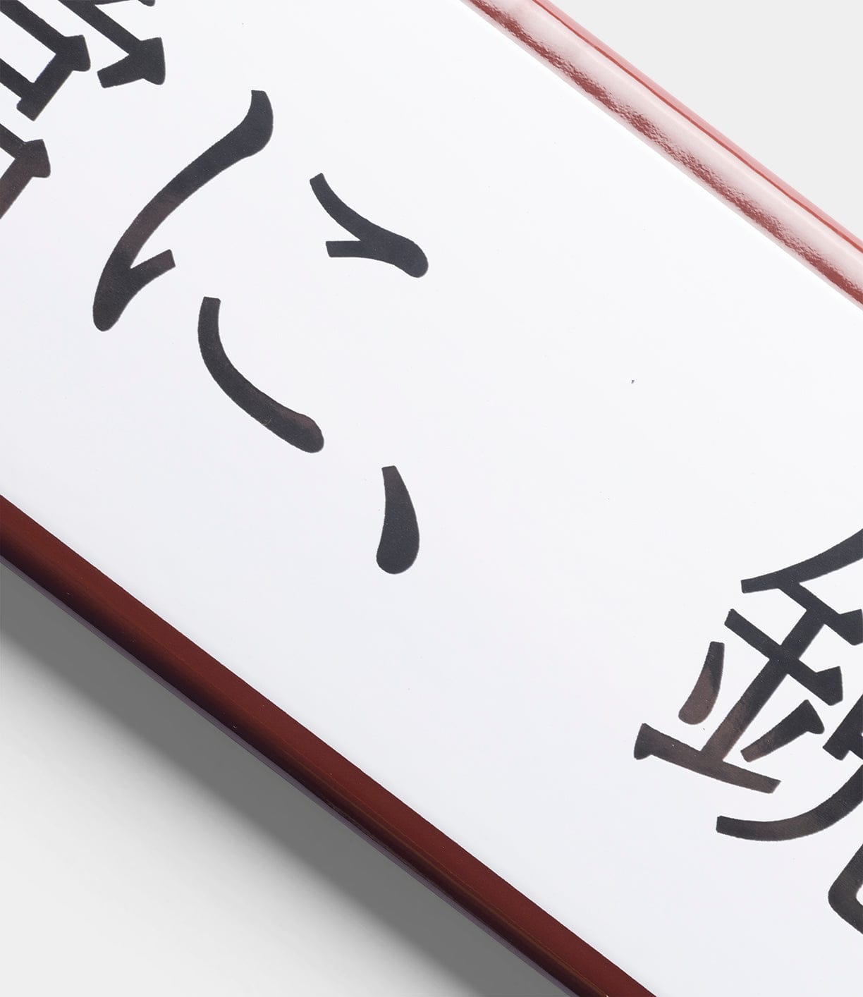 The “Stay Sharp” Enamel Steel Sign (Kanji Edition) by Best Made Co. is a white rectangular sign with black Japanese kanji and a dark brown border, shown angled and partly cropped on a light gray background.