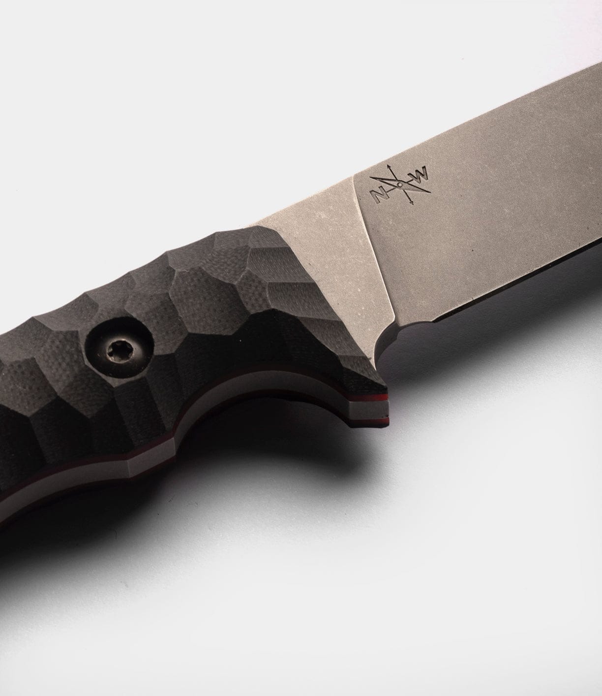Close-up of the Best Made Co NWBW Field Knife (BMC Edition) featuring a textured black handle and matte American D2 tool steel blade with an engraved logo near the hilt, shown against a plain white background.