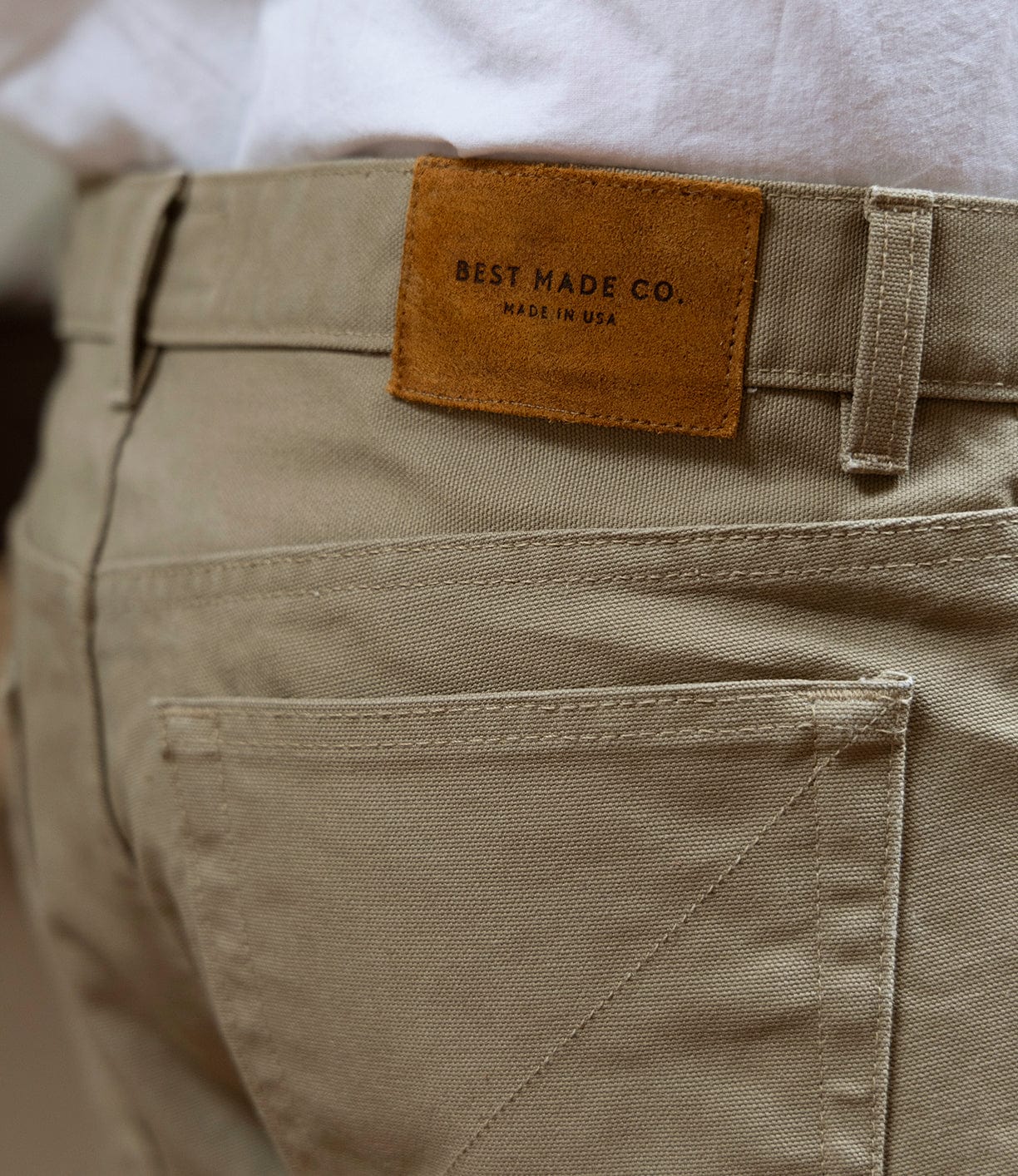 Close-up of the back pocket and leather brand patch on the Canvas 5-Pocket Pant Mark 2 - Undyed by Best Made Co, featuring "BEST MADE CO. MADE IN USA" on the patch. The wearer pairs it with a white shirt for a classic straight leg style.
