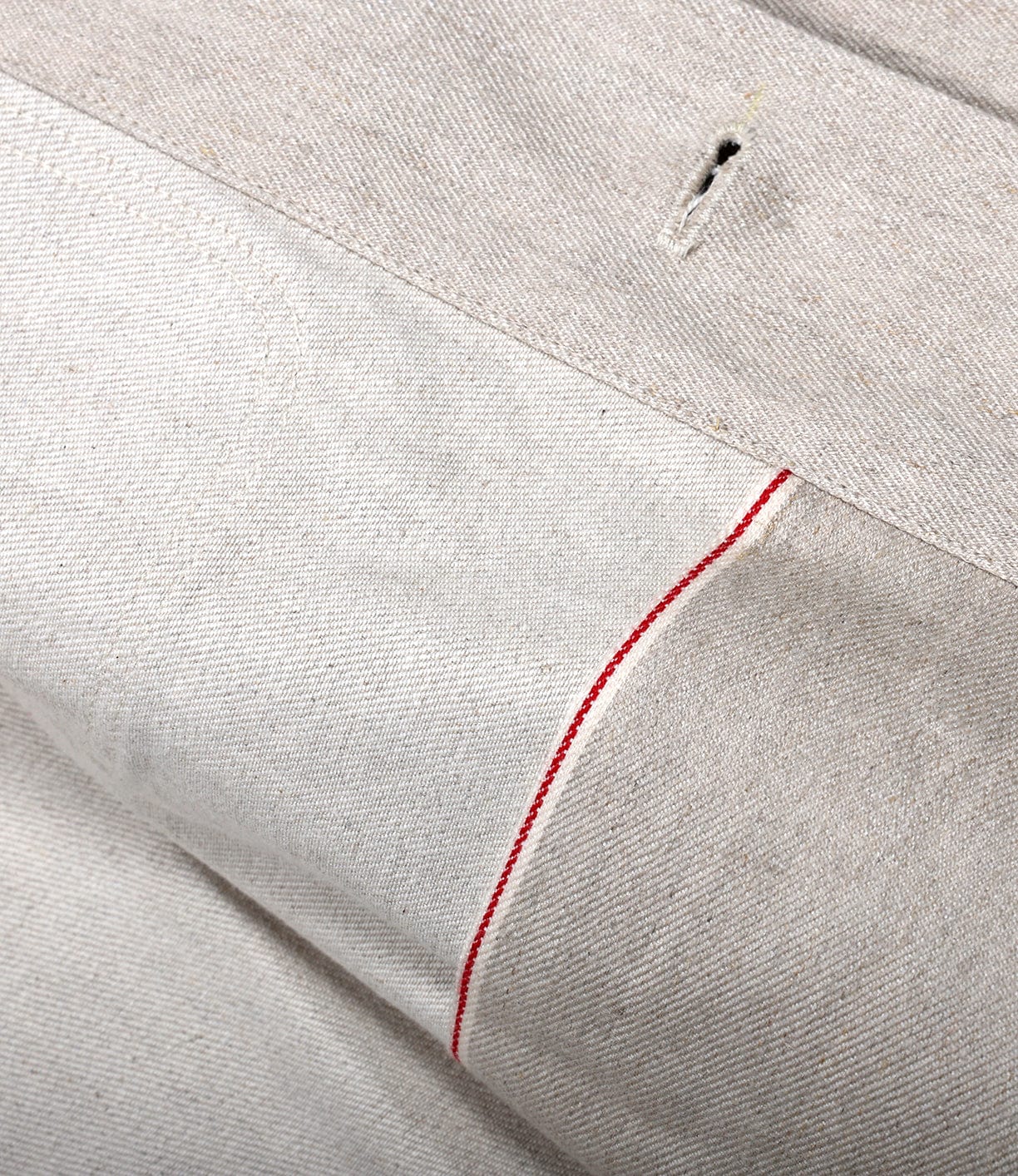 Close-up of the Selvedge Beige Studio Jacket by Best Made Co: hemp cotton denim fabric with a single red stitch line and small vertical buttonhole, showcasing rich texture and American craftsmanship.
