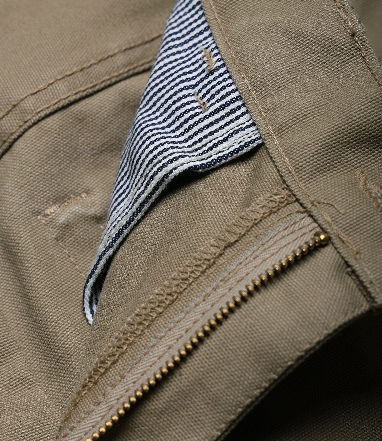 Close-up of the Best Made Co Canvas 5-Pocket Pant Mark 2 - Undyed, featuring a striped fabric lining, brass zipper, and detailed stitching along the seams inside these classic straight leg canvas pants.