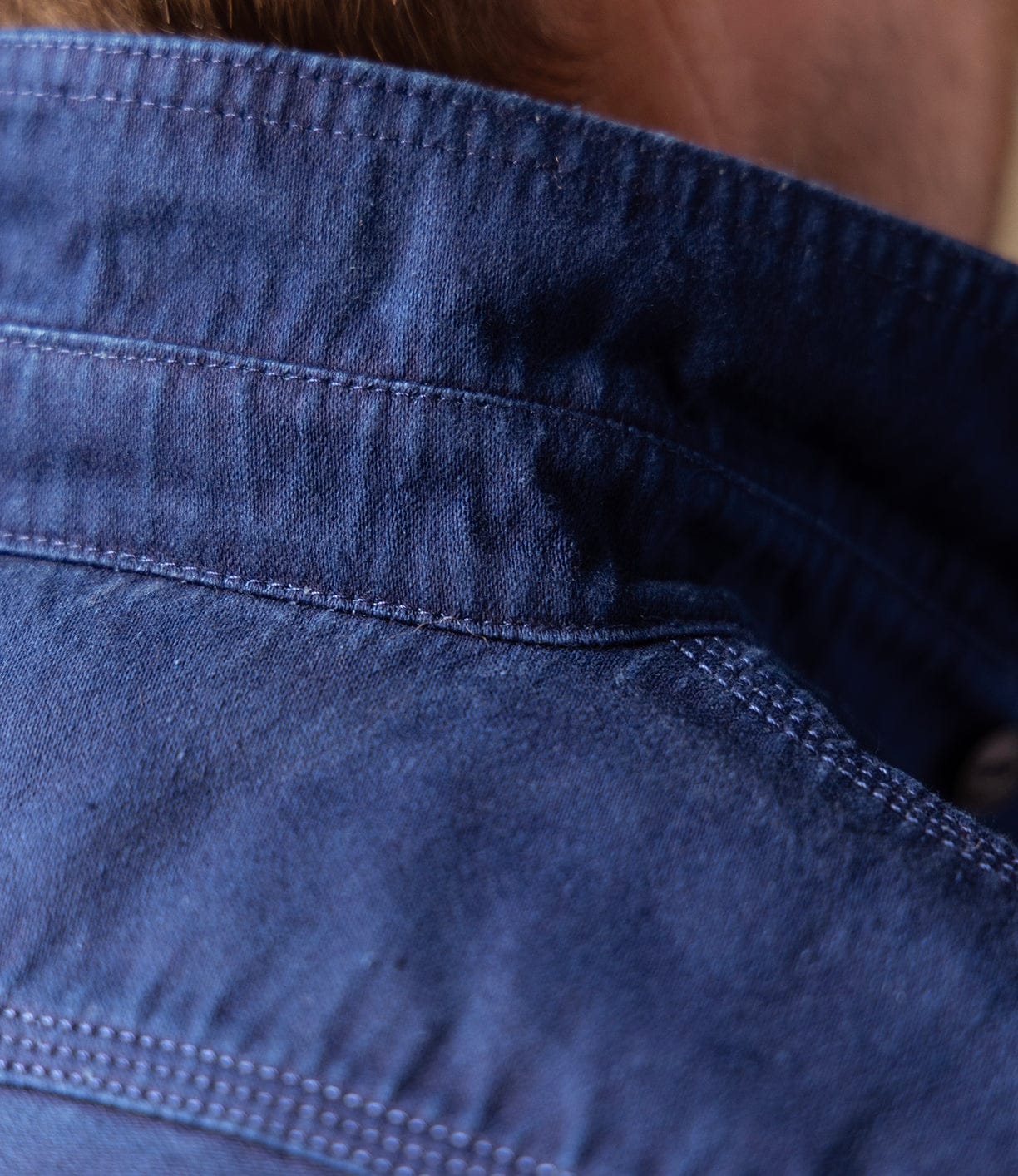 Close-up of the back neckline and shoulder of a Best Made Co Indigo Moleskin Work Shirt, showing detailed stitching and high-density fabric. Light brown hair is slightly visible at the top.