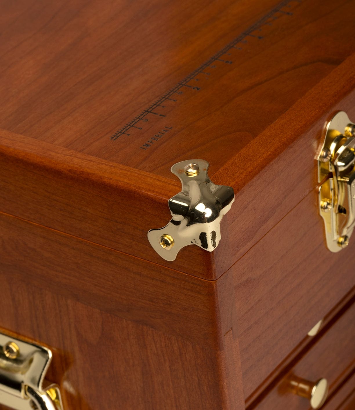Close-up of a Gerstner 41D Founder’s Edition cherry tool chest by Best Made Co., featuring shiny gold hardware like a latch and corner protector, plus an IMPERIAL measuring scale reminiscent of classic Gerstner chests.