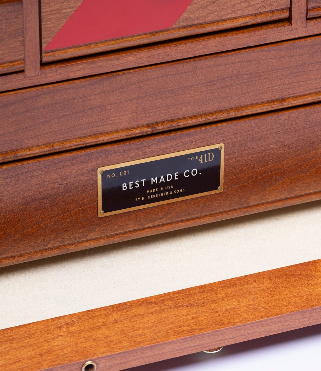 A close-up of the Gerstner 41D Founder’s Edition tool chest by Best Made Co., featuring a metal “NO. 001, TYPE 41D” label, polished cherry wood finish, and red trim for a classic American look.