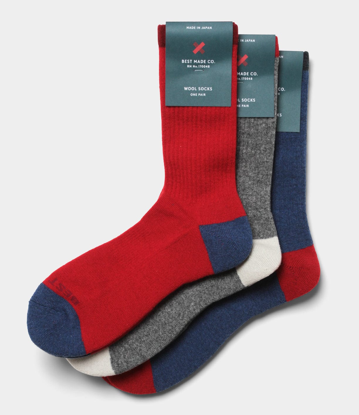 Three pairs of Standard Wool Socks by Best Made Co in red, gray, and blue with contrasting toes and heels. Made in the USA, these crew socks are ideal for everyday wear.
