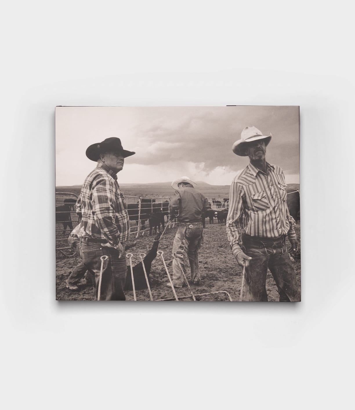 Three cowboys in hats and plaid shirts stand on a ranch with cattle behind them in this black-and-white image from Open Range by Best Made Co., evoking the timeless, vintage style of classic photography books.