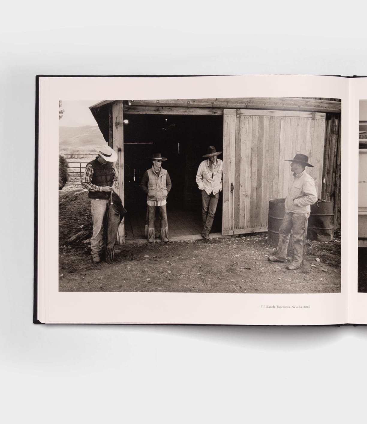 Open Range by Best Made Co. is a black-and-white photo of four cowboys in hats and boots chatting before a barn—an image that echoes classic photography books with its evocative, rustic ranch scene.