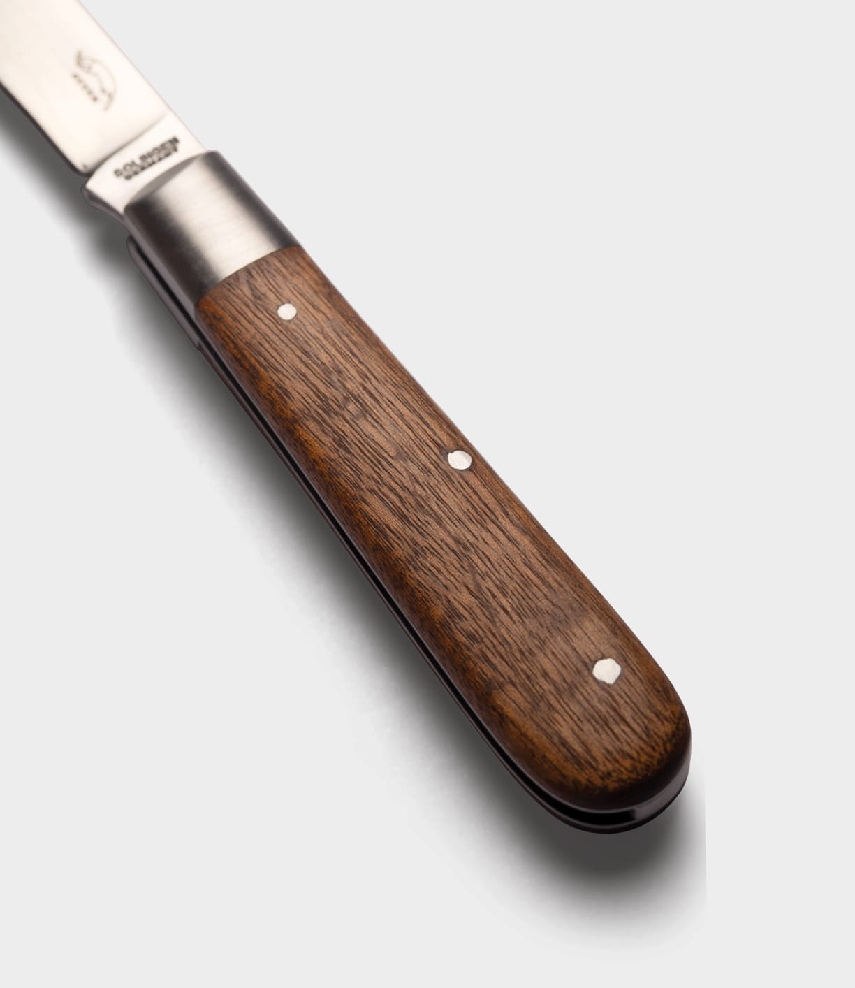 Close-up of the Best Made Co. Otter-Messer Pocket Knife, showcasing a dark polished sapele handle with three metal rivets and a carbon steel blade against a plain white background.