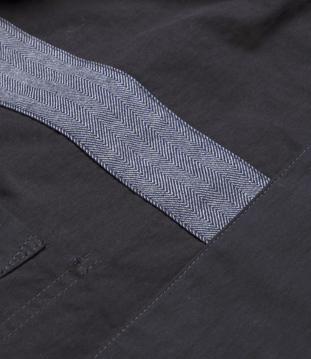 Close-up of the Best Made Co Possibilities Jacket Navy, showing its dark Japanese woven fabric and blue-and-white herringbone trim. The lightweight, durable jacket includes a stitched pocket on the left side.