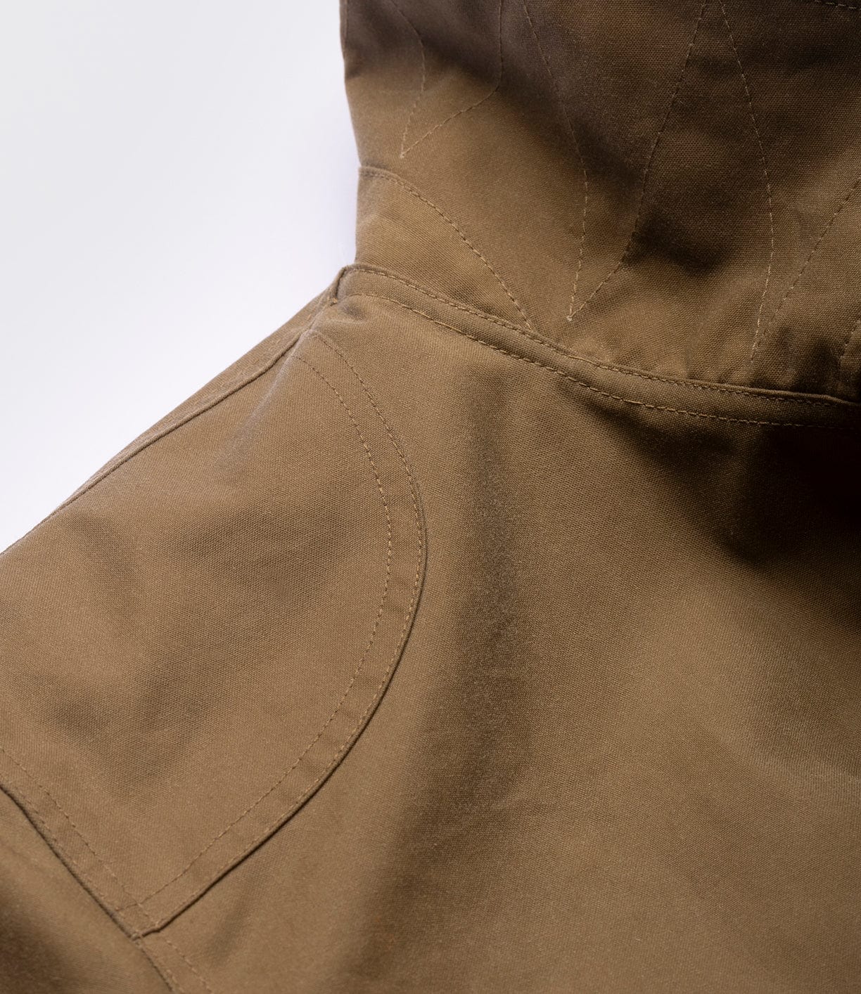 Close-up of the Best Made Co. Wool-Lined Waxed Field Jacket in tan, featuring visible seam details and a hood, shown against a plain white background.