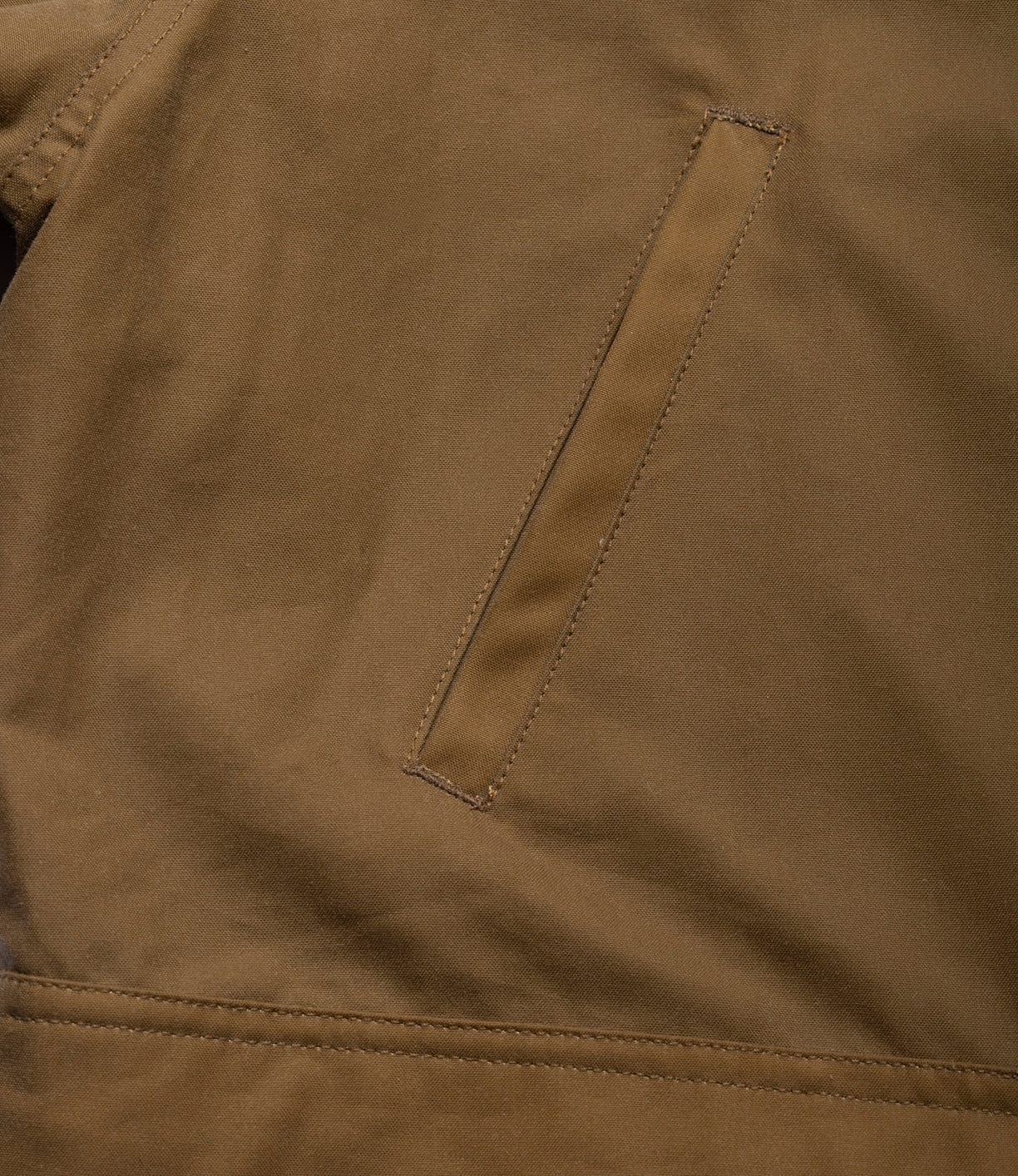 Close-up of the Best Made Co. Wool-Lined Waxed Field Jacket in Tan, featuring weather-resistant, matte fabric with visible stitching and a single slanted welt pocket.
