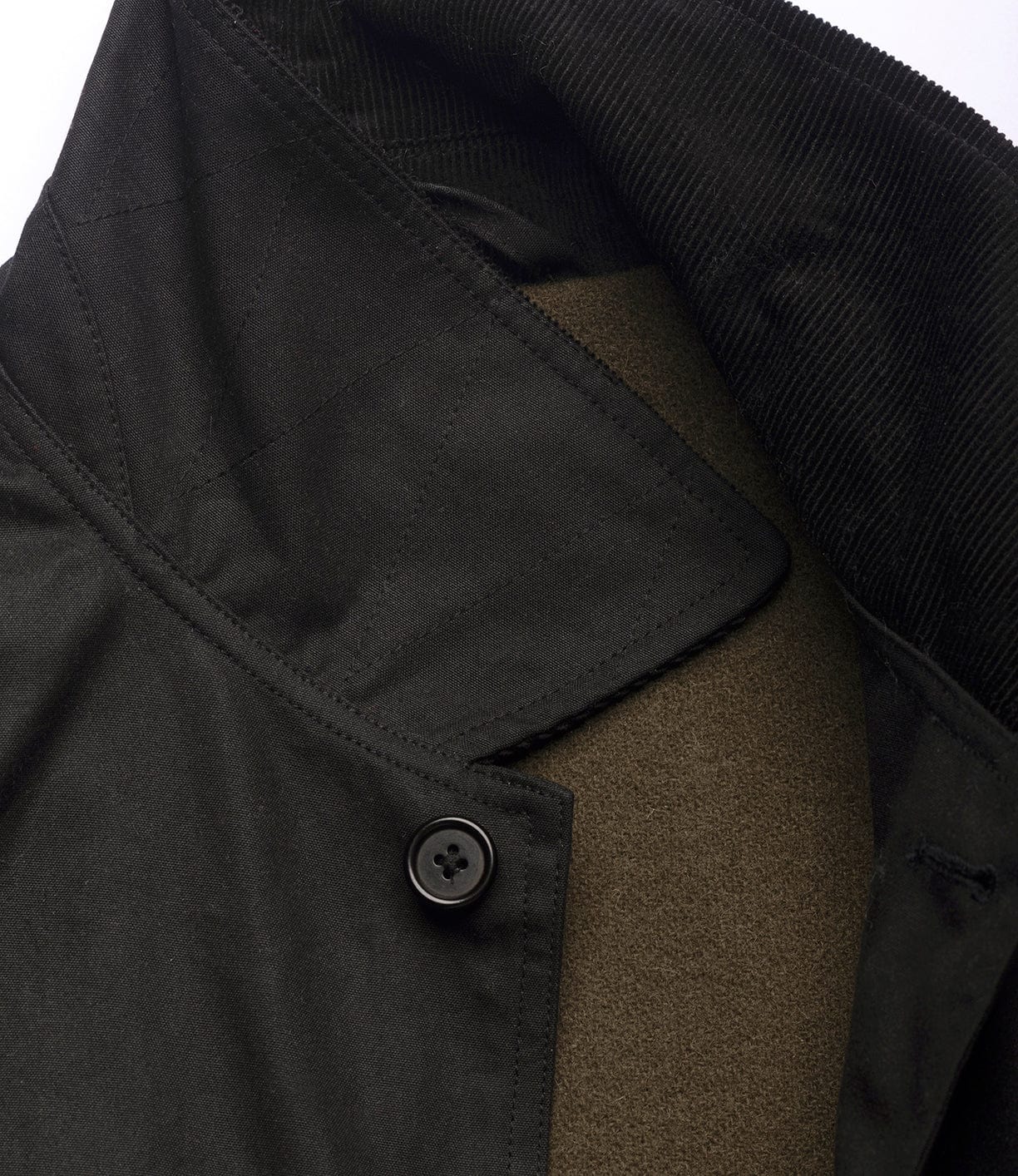 Close-up of the Best Made Co. Wool-Lined Waxed Field Jacket Black collar, featuring corduroy texture, a single black button, and a visible olive green wool lining underneath.