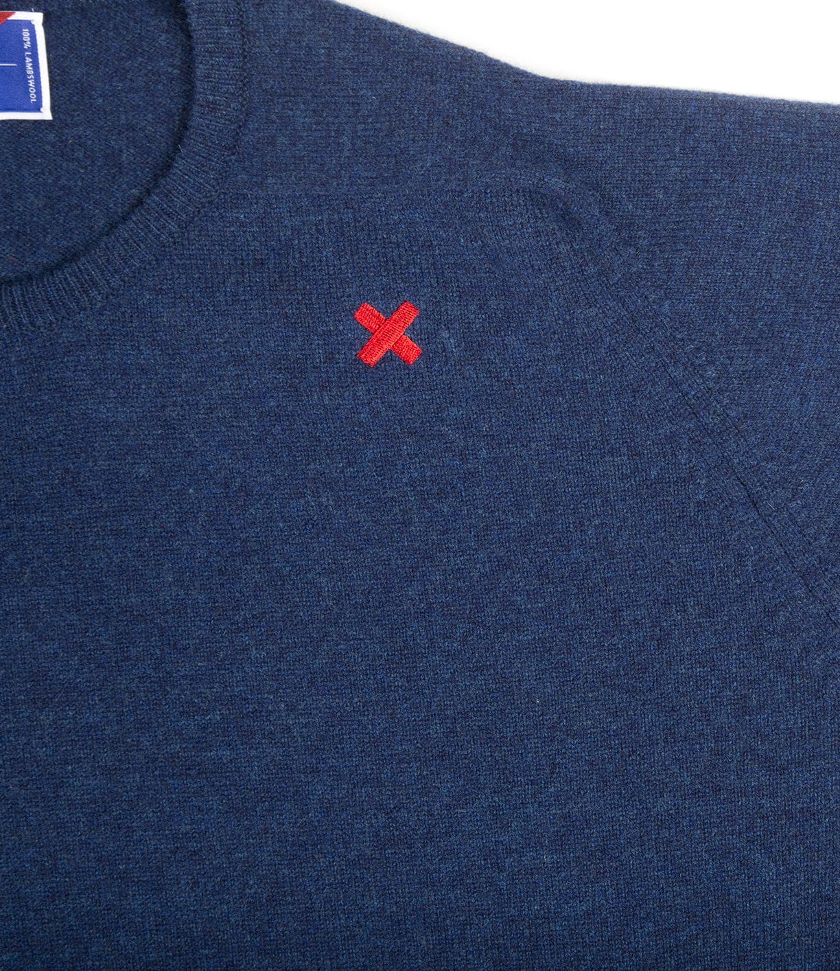A close-up of the Best Made Co. Lightweight Shetland Sweater, crafted in Scottish woolen mills from fine lambswool, with a small red X stitched near the left shoulder.
