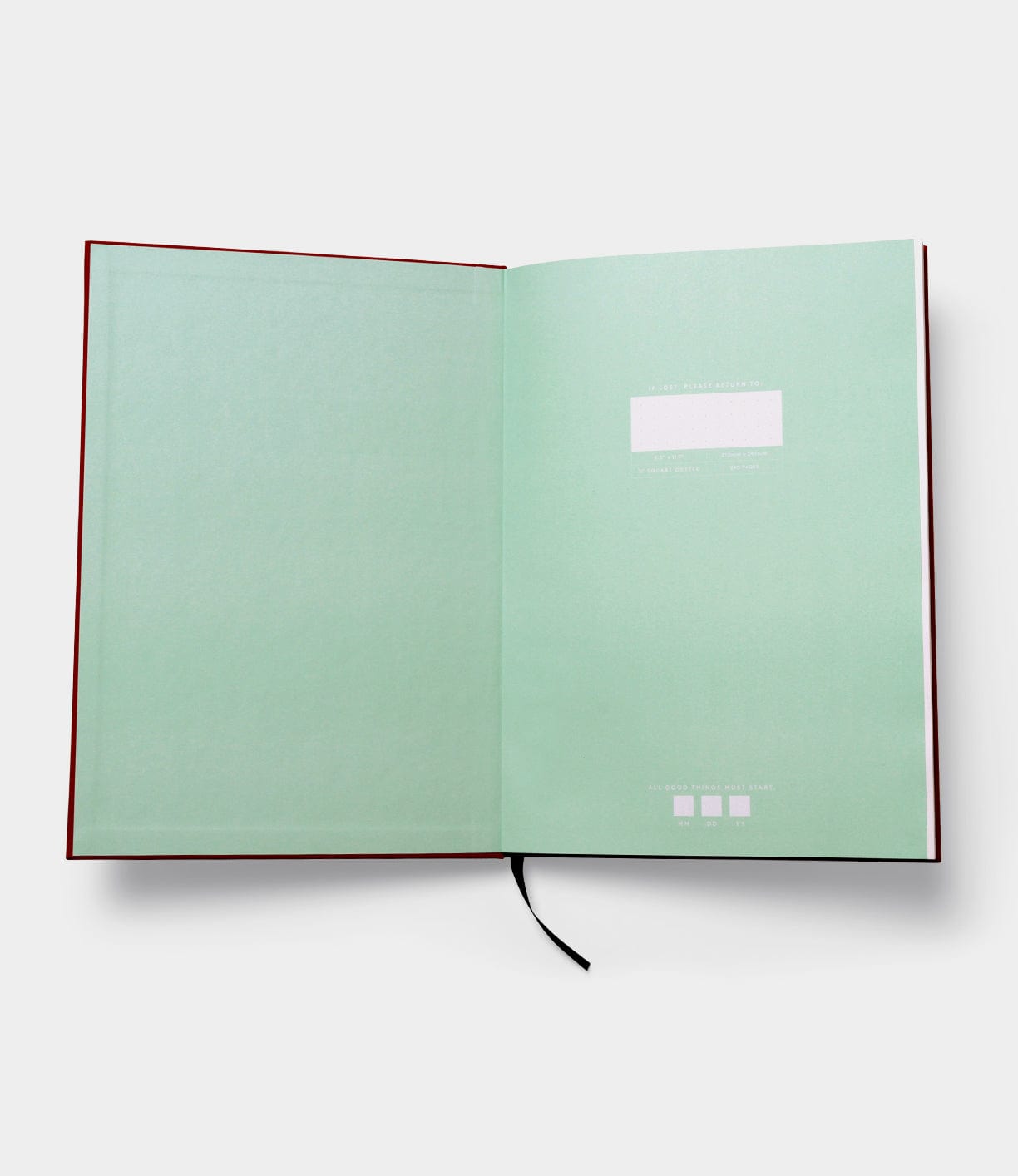 The Best Made Co. S.B.T. Max Cloth-Bound Notebook opens flat with mint green endpapers, a black ribbon bookmark, white label on the right page, subtle text at the bottom, and numbered pages for organized note-taking.