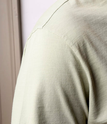 Close-up of a person wearing the Best Made Co. Standard Pocket T-Shirt Haze in light beige. The Peruvian tangüis cotton’s texture and stitching are visible, while an out-of-focus background highlights this durable everyday staple.