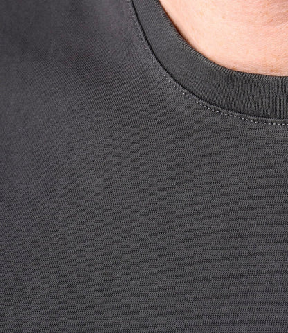 Close-up of a person wearing the Best Made Co. Standard T-Shirt in Faded Black, showing part of the neck, collar, and soft tangüis cotton fabric.