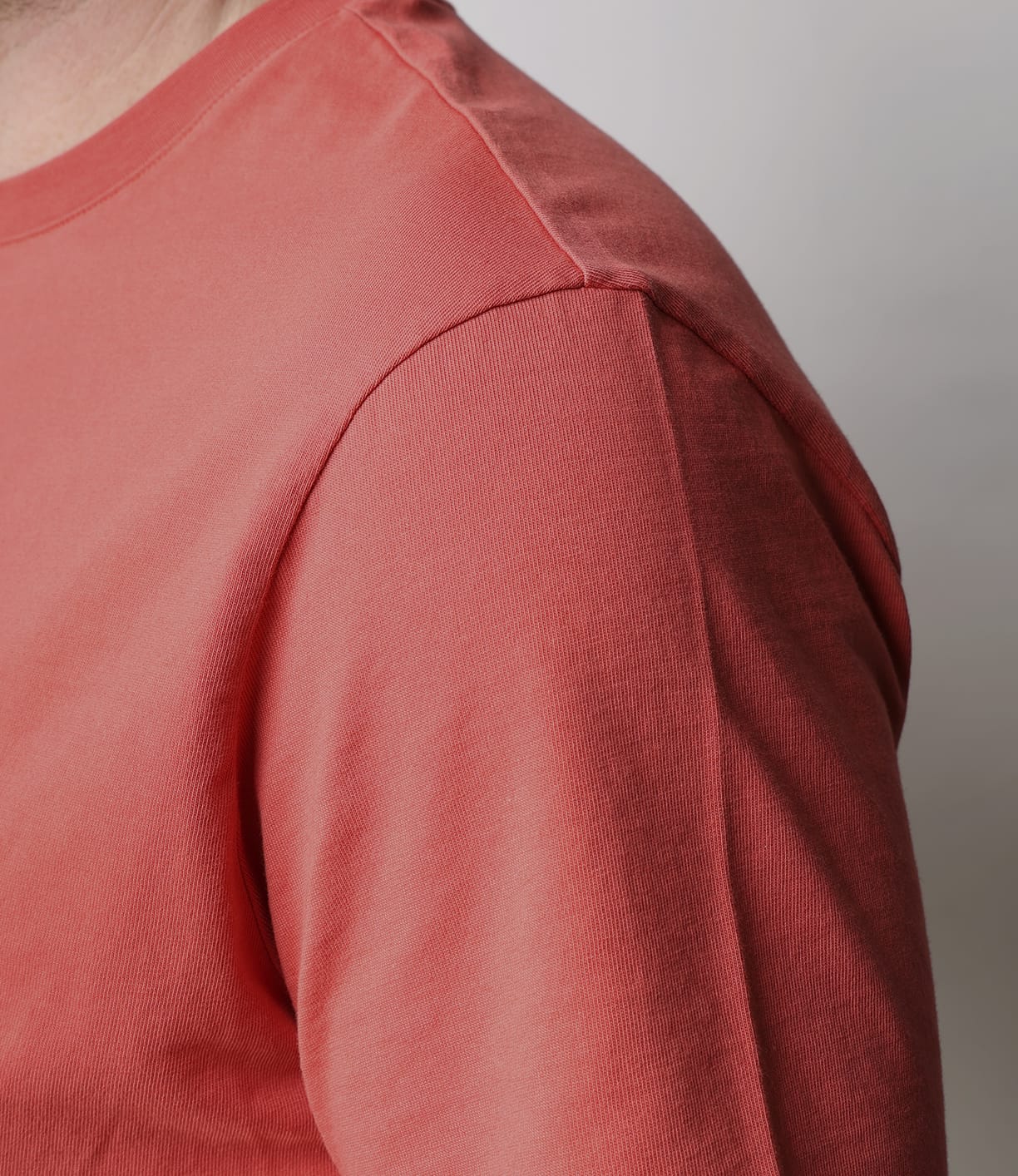 Close-up of a person wearing the Best Made Co Standard T-Shirt in Faded Red, crafted from soft Peruvian Tangüis cotton. Visible seam details highlight this durable everyday staple against an out-of-focus neutral background.