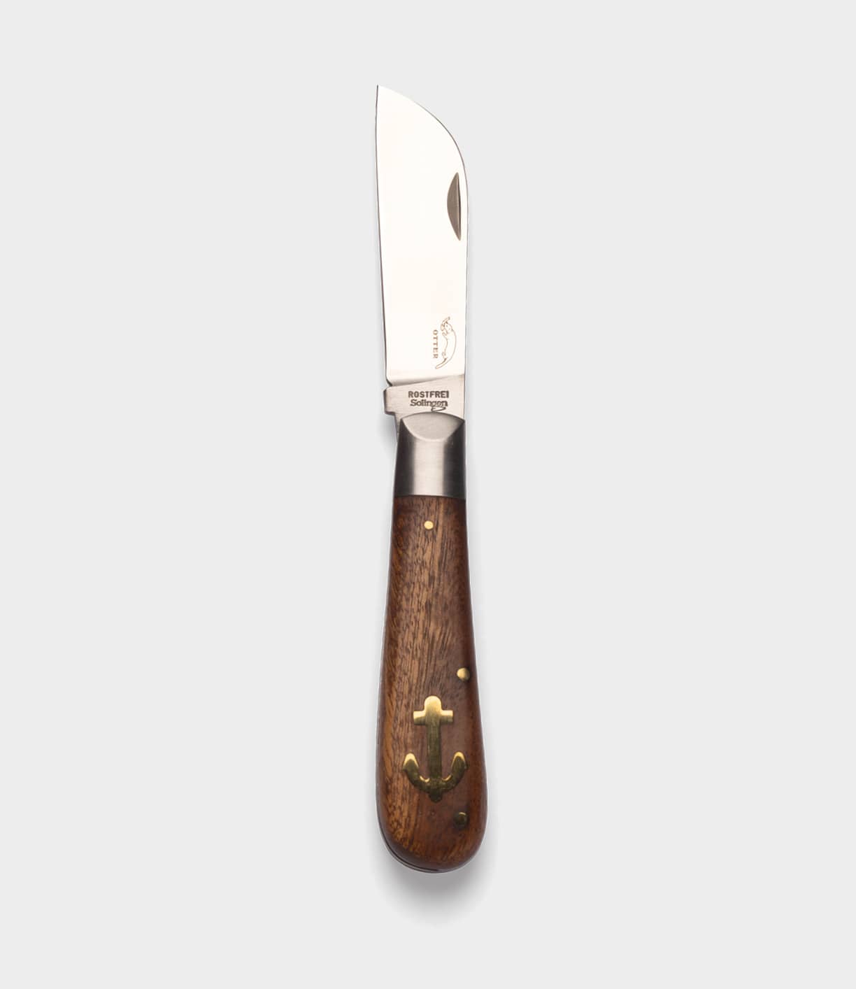 The Best Made Co. Anchor Knife features a polished metal sheepsfoot blade, a dark wooden handle with brass anchor inlay and rivets, displayed on a plain light gray background.