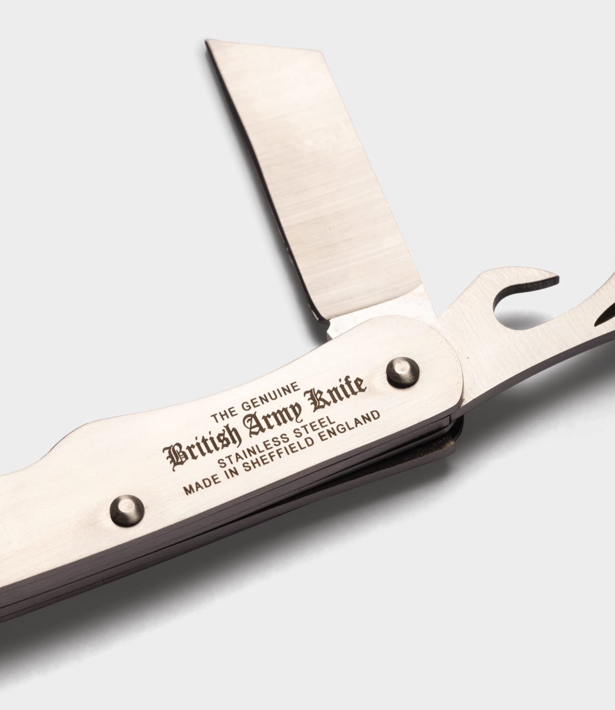 A close-up of an open British Army Knife by Best Made Co., featuring two blades and a handle engraved with “The Genuine British Army Knife, Stainless Steel, Made in Sheffield England,” shown against a plain white background.