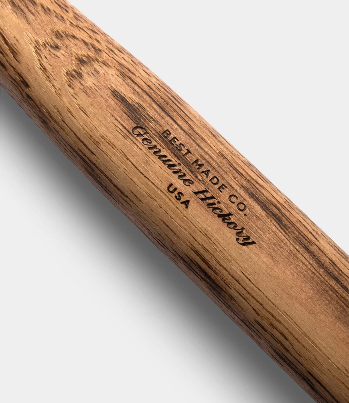 Close-up of a Spark (Straight-Hold Edition) handle by Best Made Co., featuring 'BEST MADE CO. Genuine Hickory USA' burned into the Appalachian hickory. The distinct grain is visible, ideal for pairing with a high-carbon steel axe or leather blade guard.