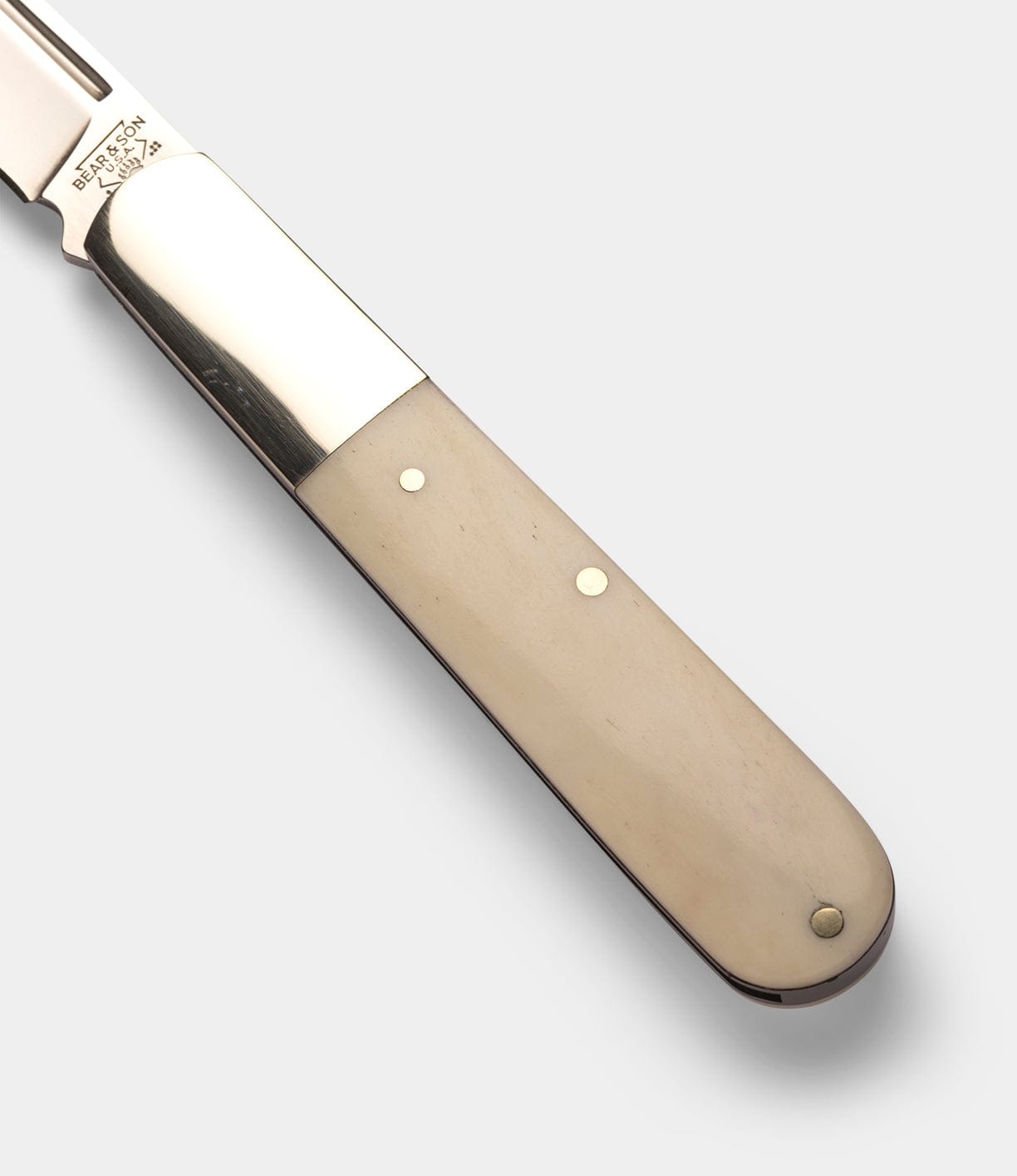 Close-up of the Best Made Co Barlow Knife, showcasing its polished bone handle with two metal rivets, shiny metal bolster, and stainless steel blade on a plain light gray background.
