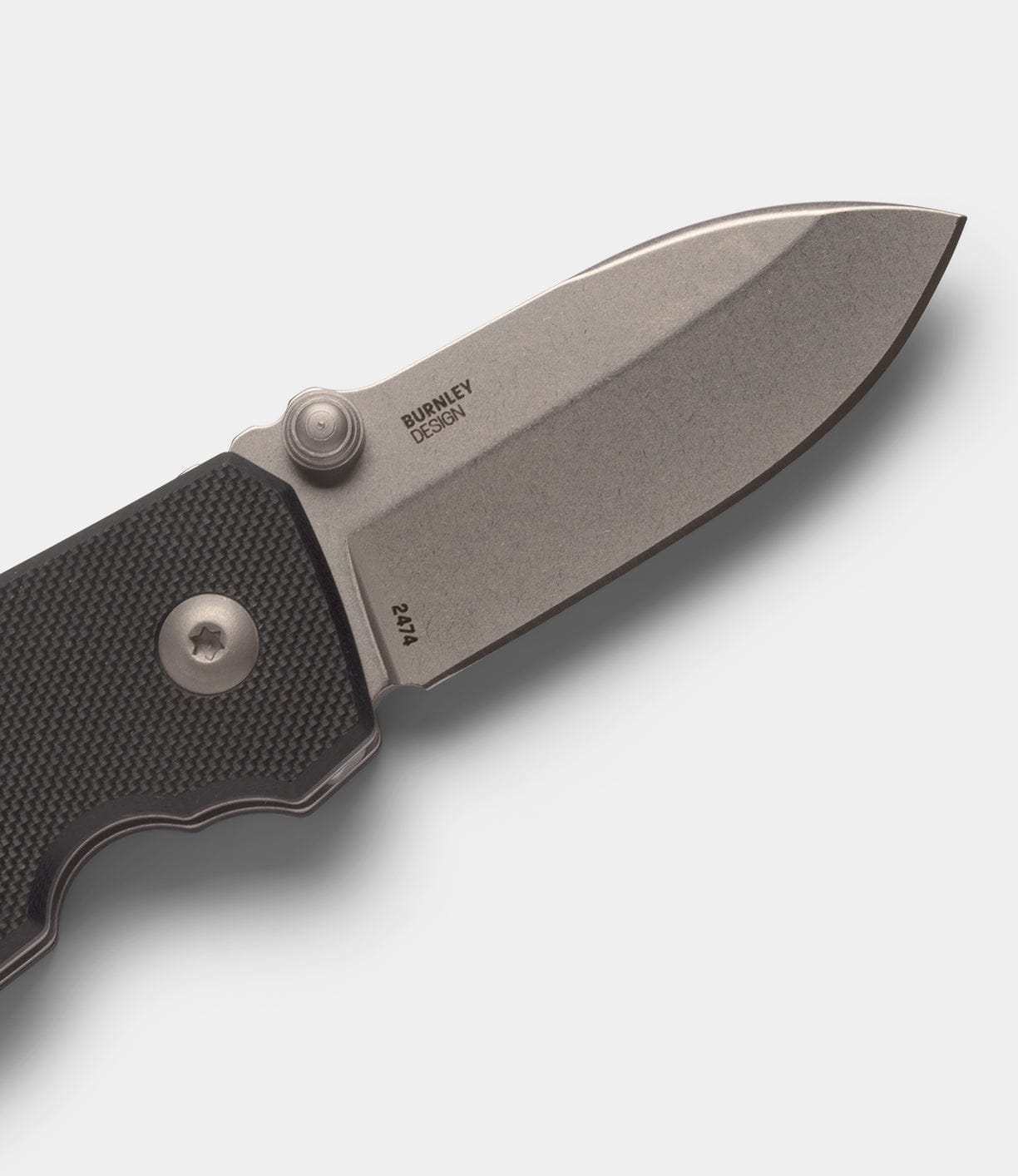 A close-up of the Best Made Co CRKT Squid knife, featuring a textured black handle and stonewashed D2 steel blade with pivot screw, thumb stud, and Burnley Design engraved on the blade.