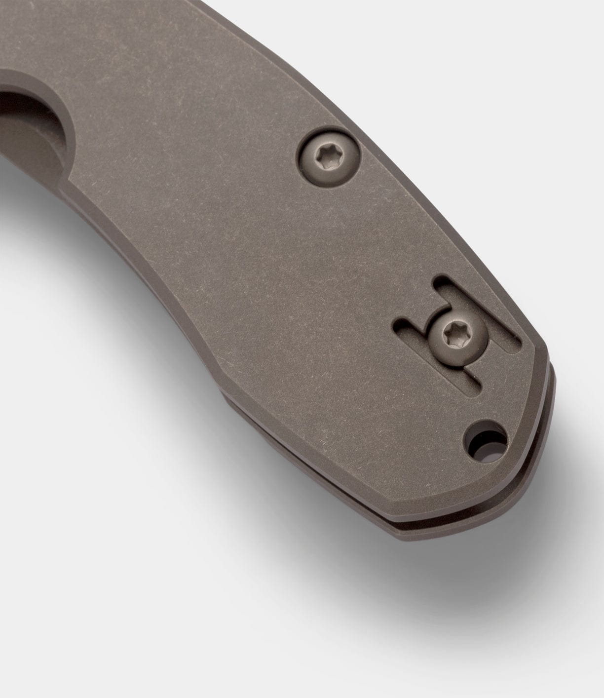 Close-up of the end of a metallic gray Spyderco Techno 2 pocket knife handle by Best Made Co, showing two screws, a cutout slot, and a titanium framelock against a plain white background.