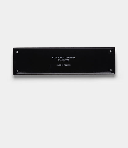 A rectangular black enamelware sign with four corner holes. The durable “Stay Sharp” Enamel Steel Sign by Best Made Co. features centered white text on a plain light gray background, reading BEST MADE COMPANY ENAMELWARE MADE IN POLAND.