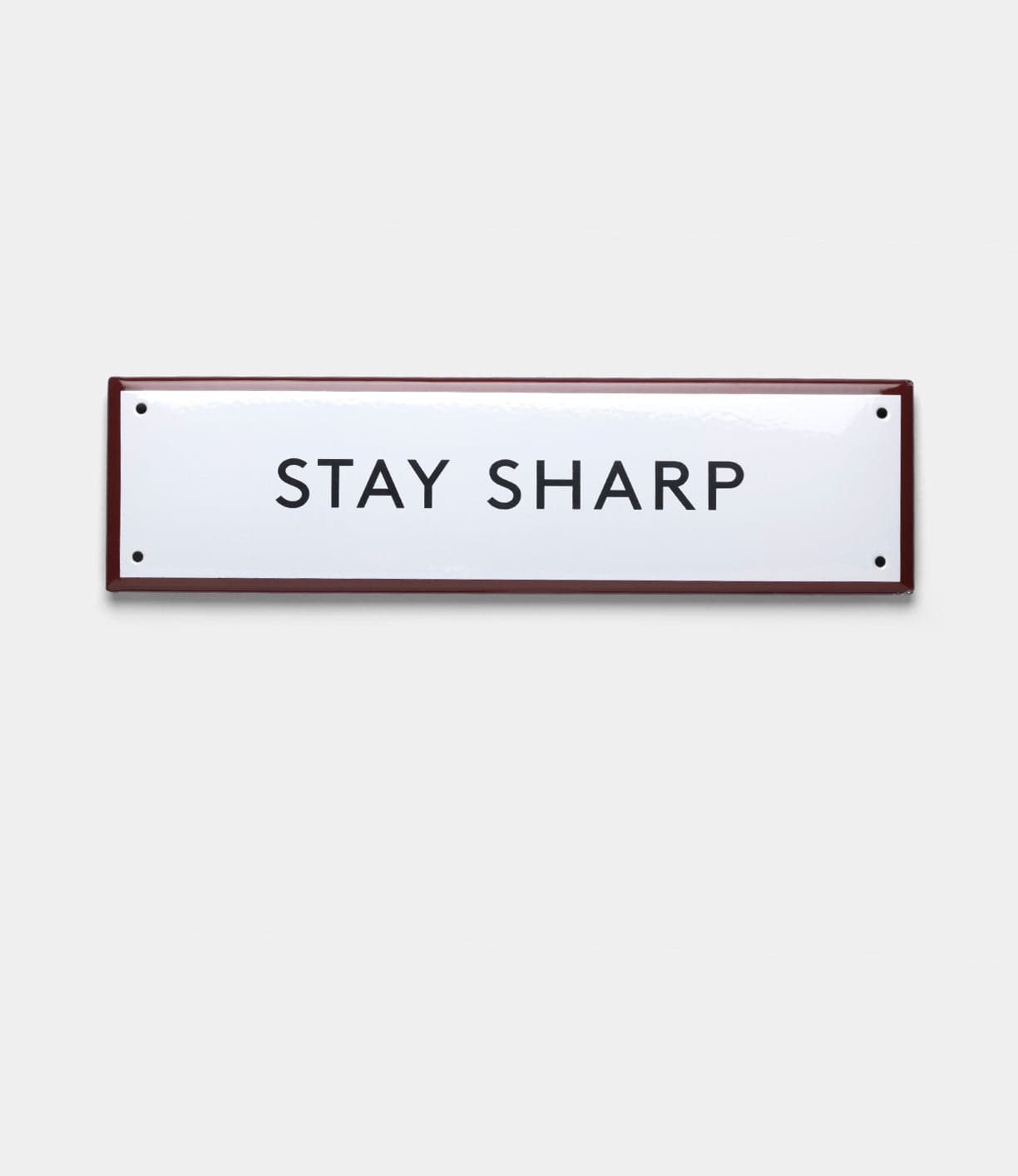 The “Stay Sharp” Enamel Steel Sign by Best Made Company Co. is a rectangular, hand-crafted white sign from Poland with a dark border and bold black capital letters.