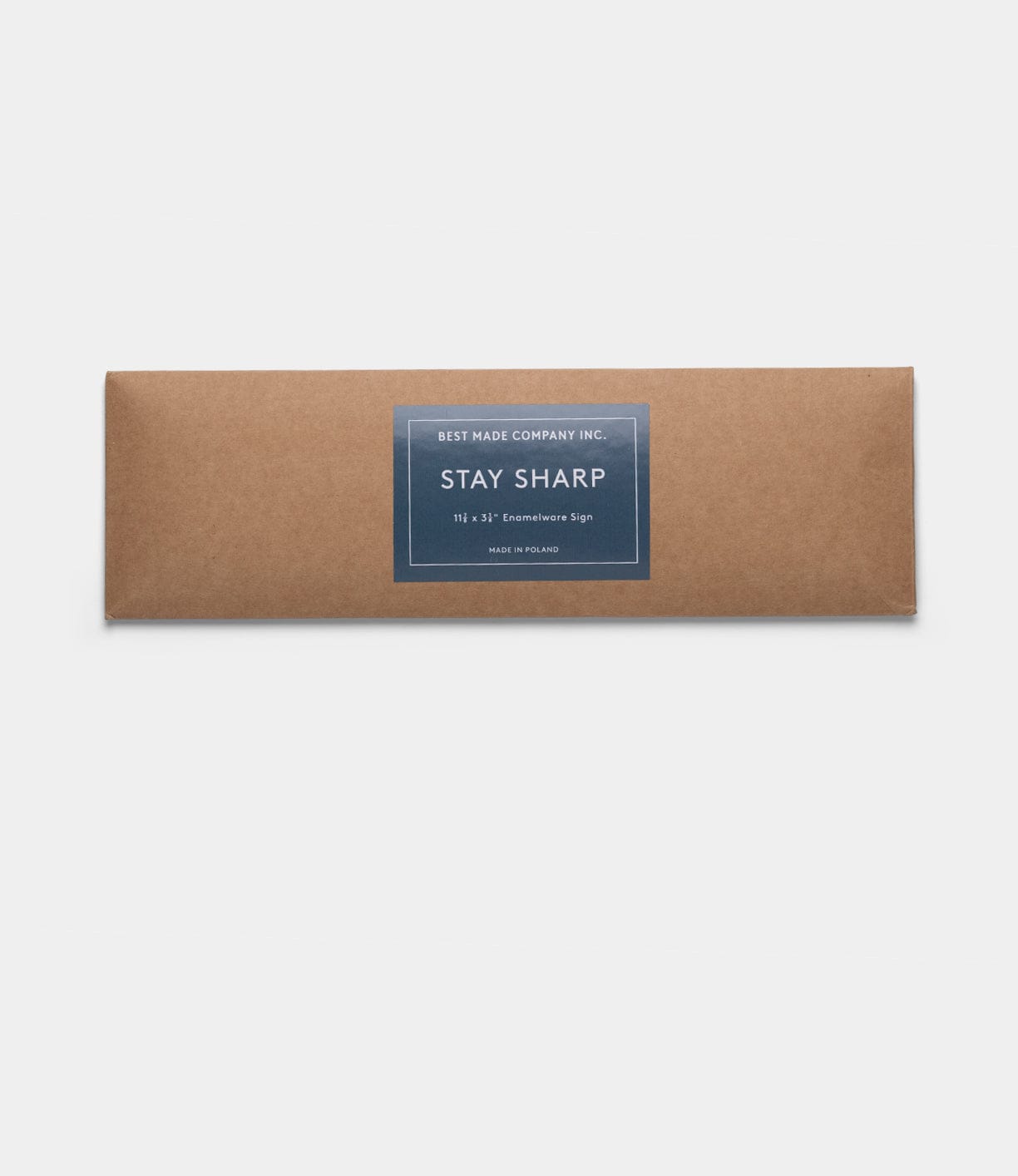 A rectangular brown box with a dark blue label reading “Best Made Company Co. Stay Sharp” Enamel Steel Sign, hand-crafted in Poland, is centered on a plain white background.