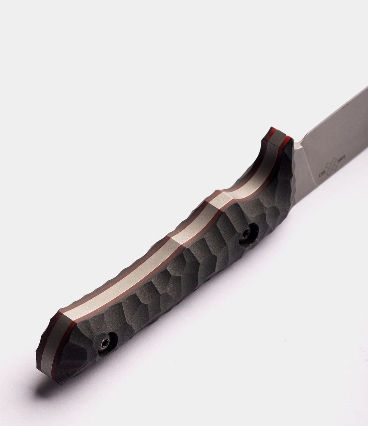 A close-up of the Best Made Co NWBW Field Knife (BMC Edition) shows its textured, dark gray handle with angular patterns and two screws. The American D2 tool steel blade is partially visible on the right against a plain white background.