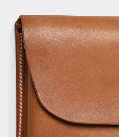 Close-up of the Best Made Co. Gfeller Case Small, a light brown, hand-stitched leather case featuring visible side stitching and a rounded flap secured by a metal rivet, inspired by the classic Gfeller Document Case design.