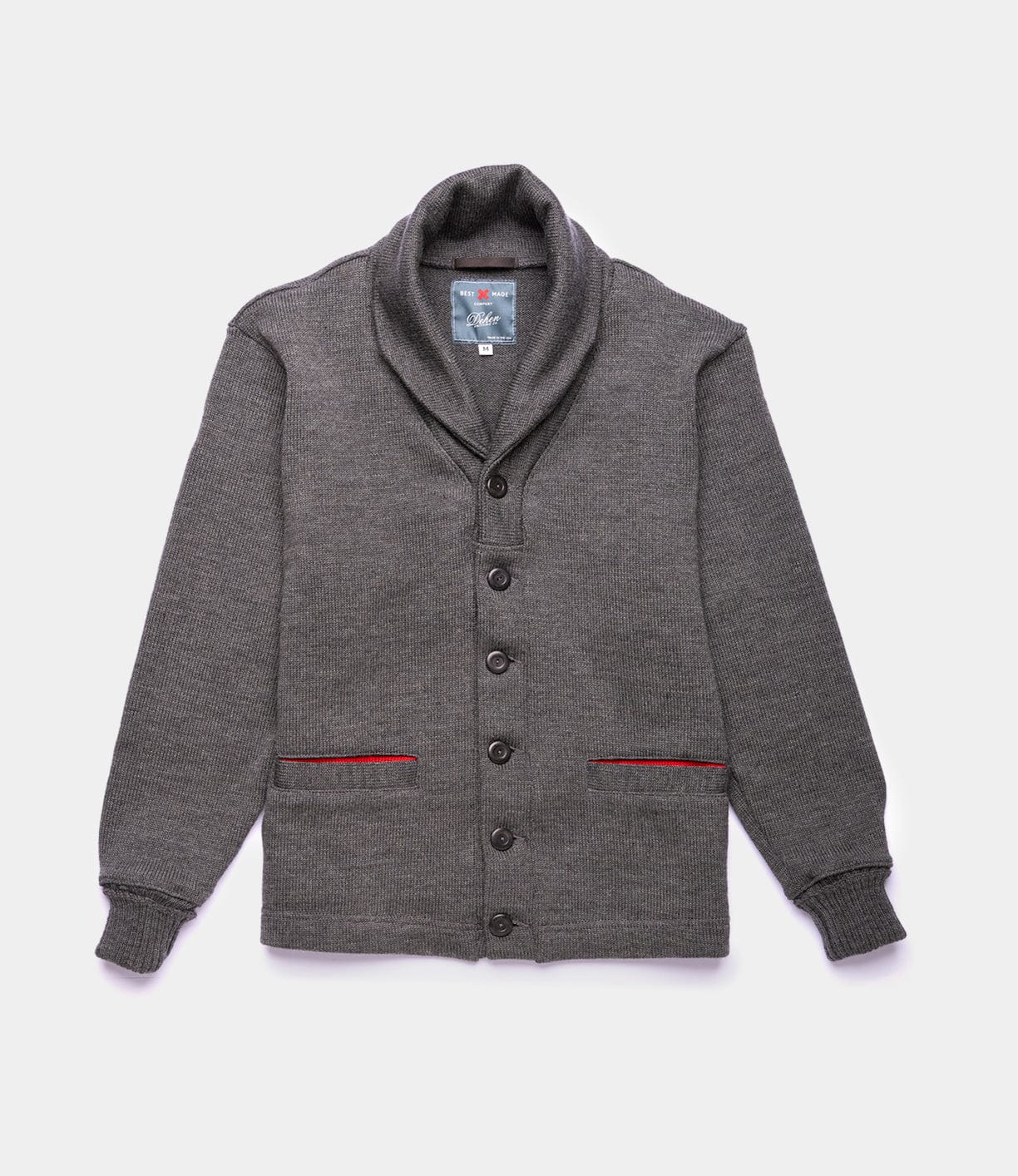 The Best Made Co. Dehen Shawl Neck Sweater Charcoal features a front button closure, two front pockets with red trim, and ribbed cuffs. Displayed laying flat on a white background.