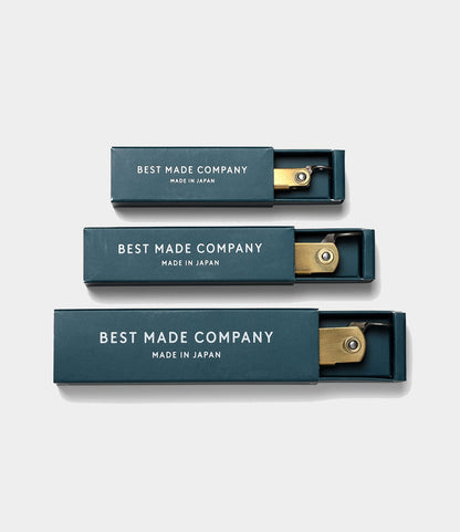 Three rectangular dark green boxes labeled Best Made Co. contain Mid Brass Higo Knives, each partially open to reveal the handmade blade inside. The boxes are arranged vertically.