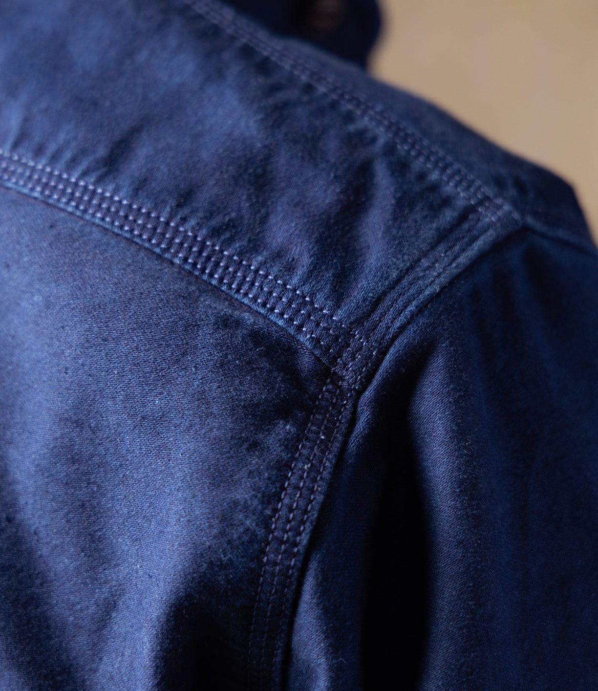Close-up of the shoulder and upper back of the Indigo Moleskin Work Shirt by Best Made Co, highlighting detailed stitching and a high-density weave texture inspired by Japanese indigo workwear.