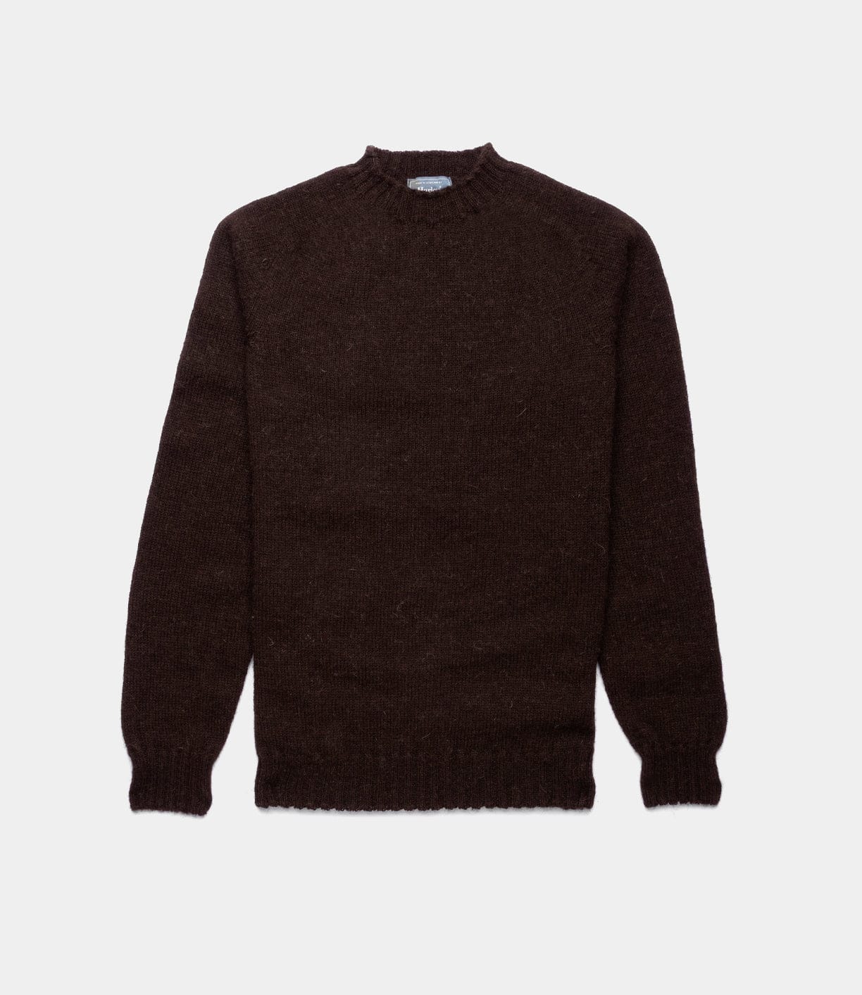 The Best Made Co. Black Sheep Sweater is a seamless-knit, long-sleeved, dark brown crewneck with ribbed cuffs and hem, crafted from classic black Shetland wool and shown laid flat on a white background.