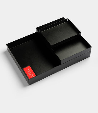 The Spare Parts Trays (Set of 3) by Best Made Co. are matte black, rectangular organizers with four compartments and a red front label—ideal for workbench or office organization, shown on a plain light background.