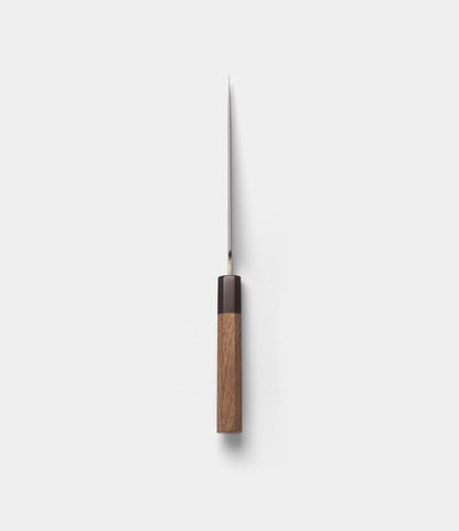A Best Made Co. Aogami Petty Knife with a wooden handle is displayed vertically from above, its san-mai blade pointing upward and centered against a plain white background.