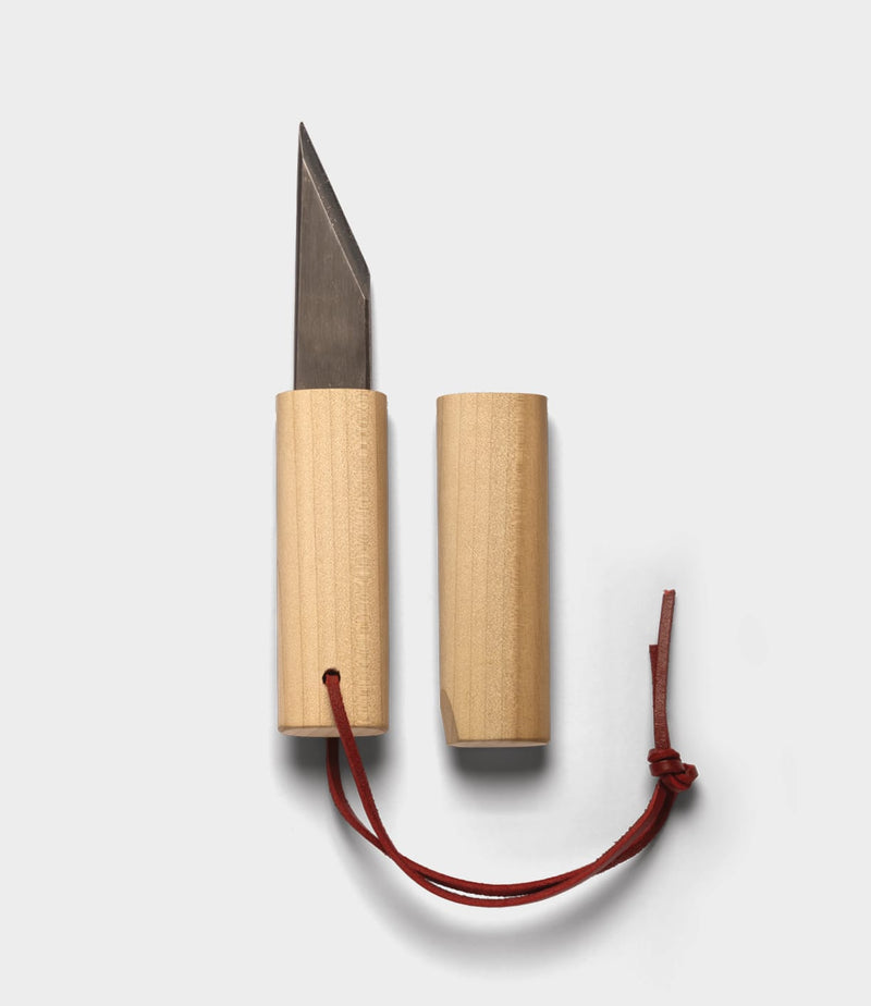 The Best Made Co. Kiridashi Knife, featuring a wooden handle and red leather strap, is shown with its sheath removed and placed beside the single-bevel blade on a plain white background.