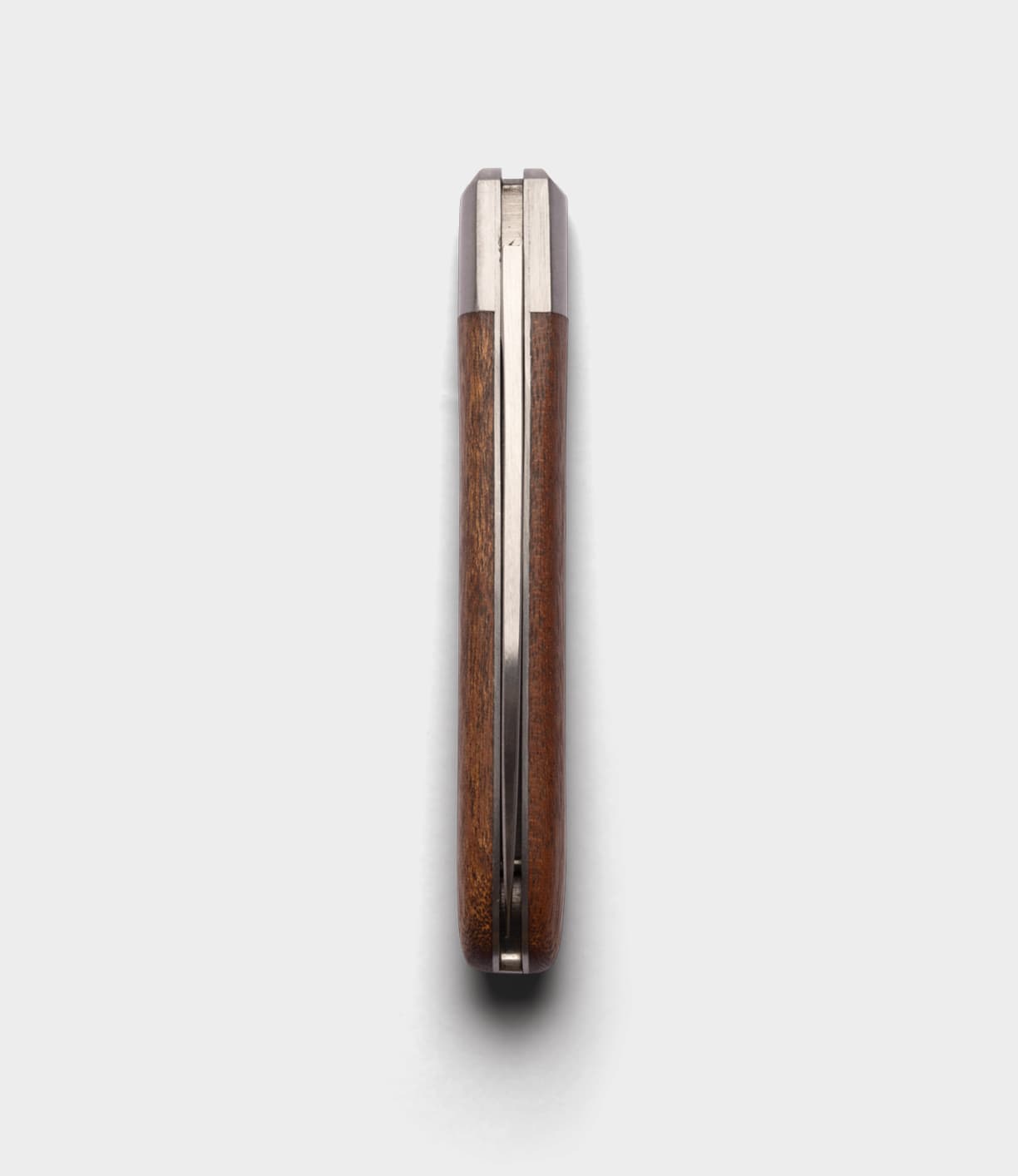 A closed Best Made Co. Otter-Messer Pocket Knife with a sapele handle is shown top-down on a white background, revealing only the carbon steel blade's edges and metal spine.