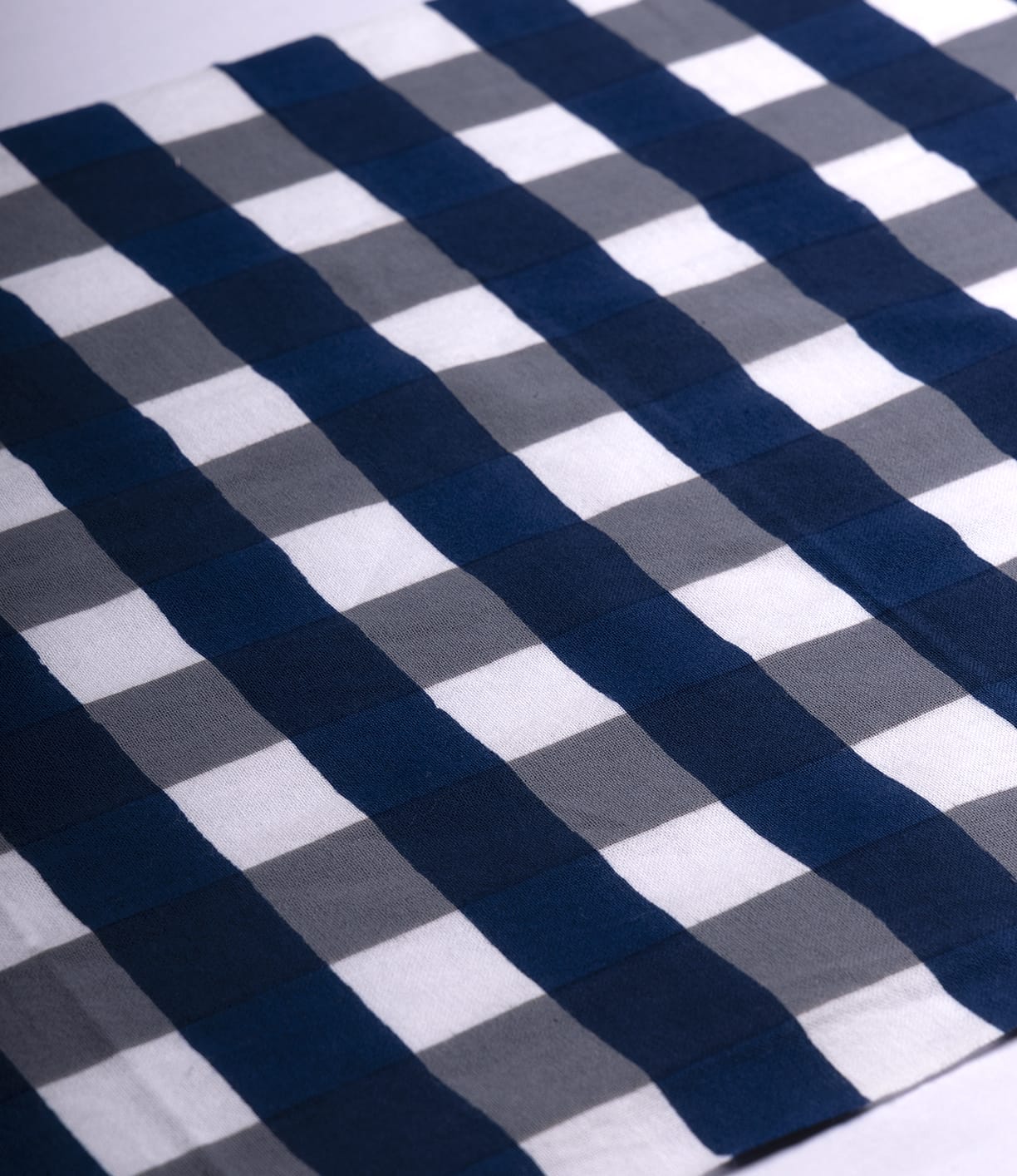 A close-up of the Benkei-Jima Tenugui by Best Made Co., a hand-dyed Japanese cloth with navy blue, gray, and white checkered stripes, capturing subtle wabi-sabi charm.