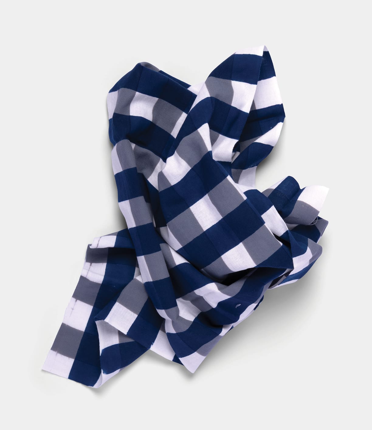 The Benkei-Jima Tenugui by Best Made Co., a hand-dyed Japanese cloth with a blue, gray, and white checkered chusen pattern, is crumpled and laid on a plain, light background.