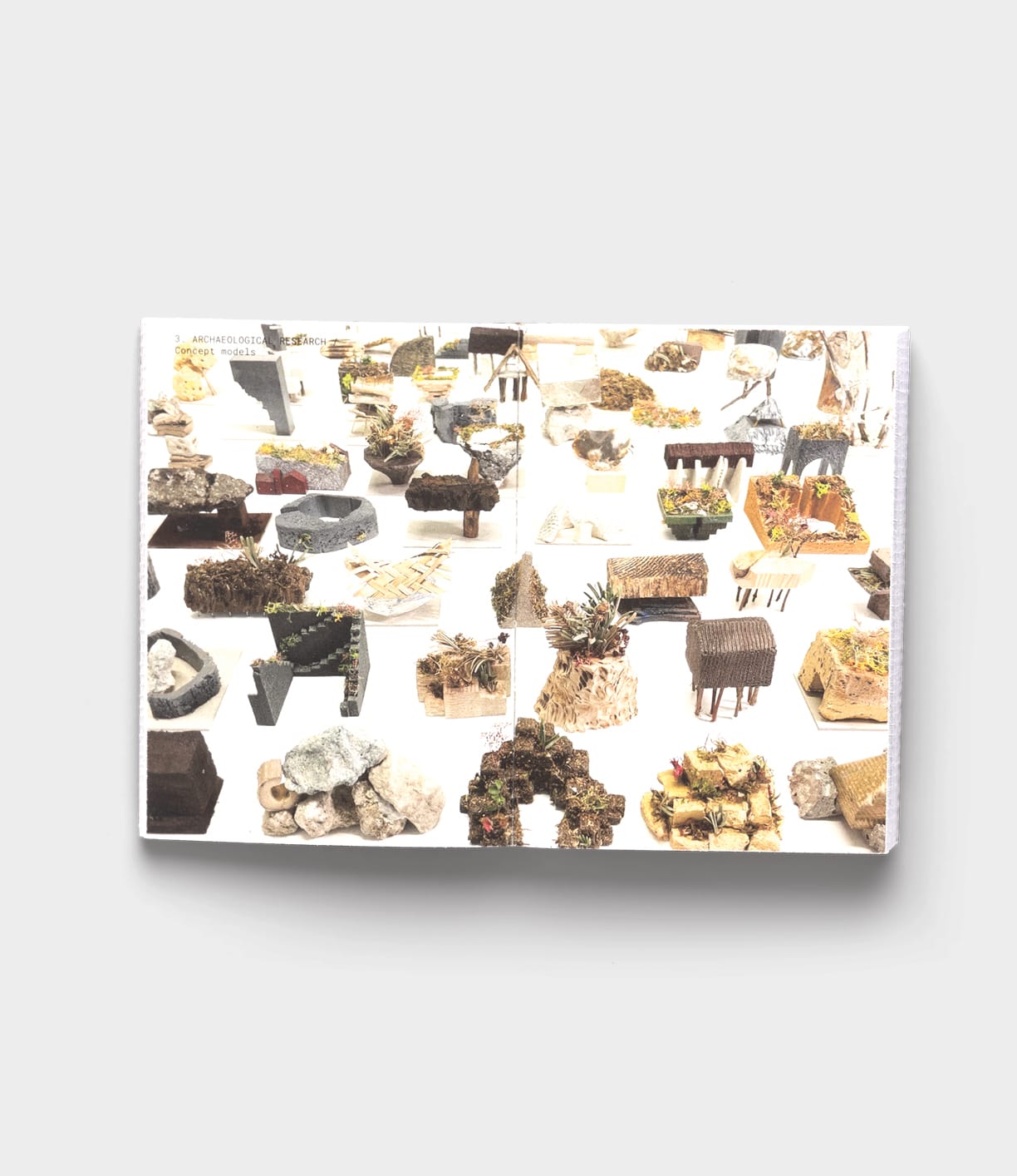 An open book displaying small sculptural objects made from natural materials reflects the sustainable design of the Tane Garden House by Best Made Co.