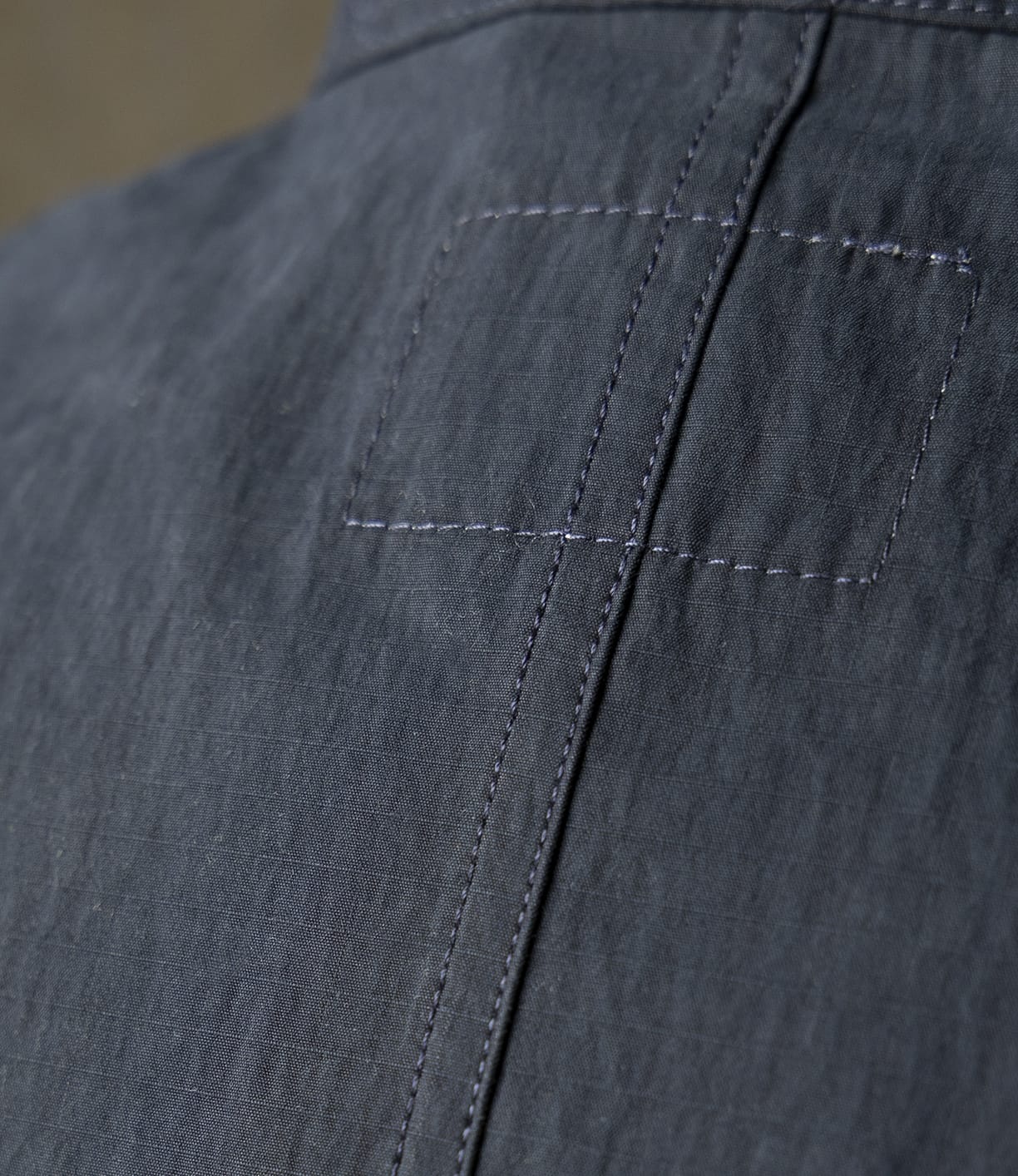 Close-up of dark blue organic cotton denim with visible stitching, a rectangular patch, and a vertical seam, highlighting the texture and detail of Best Made Co's Possibilities Jacket Navy.