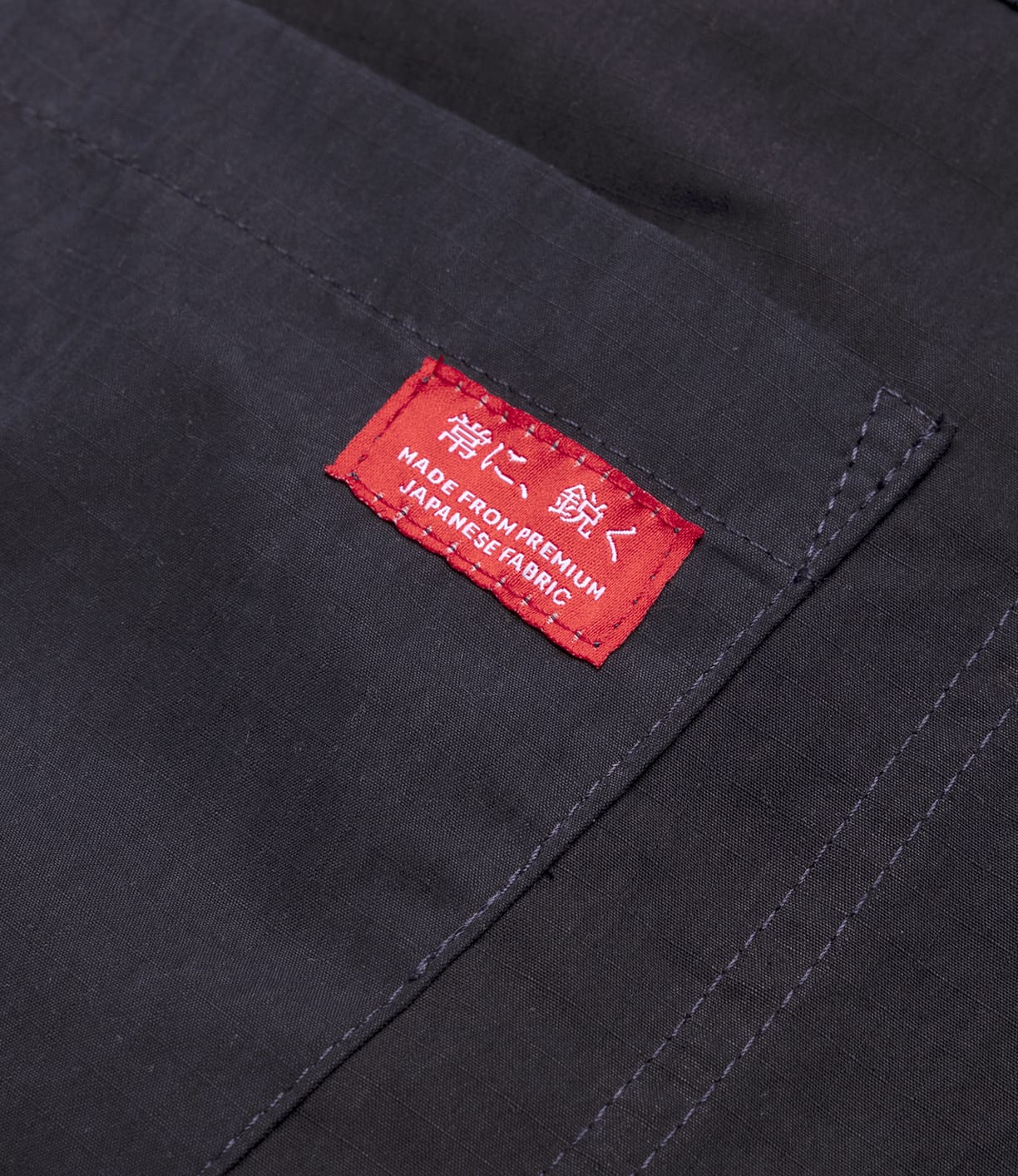 Close-up of the Possibilities Jacket Navy by Best Made Co, crafted from dark cotton Cordura ripstop. The stitched pocket features a red label reading MADE FROM PREMIUM JAPANESE FABRIC with white Japanese characters.