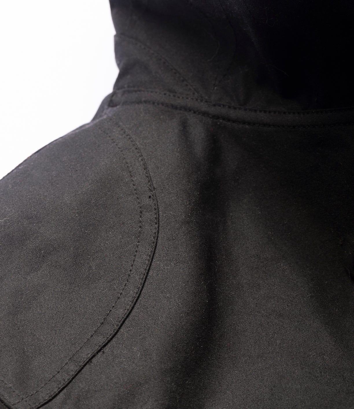 Close-up of the Best Made Co. Wool-Lined Waxed Field Jacket Black, highlighting the shoulder stitching and craftsmanship reminiscent of classic waxed jackets, set against a white background.