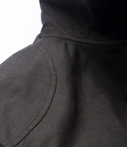 Close-up of the Best Made Co. Wool-Lined Waxed Field Jacket Black, highlighting the shoulder stitching and craftsmanship reminiscent of classic waxed jackets, set against a white background.